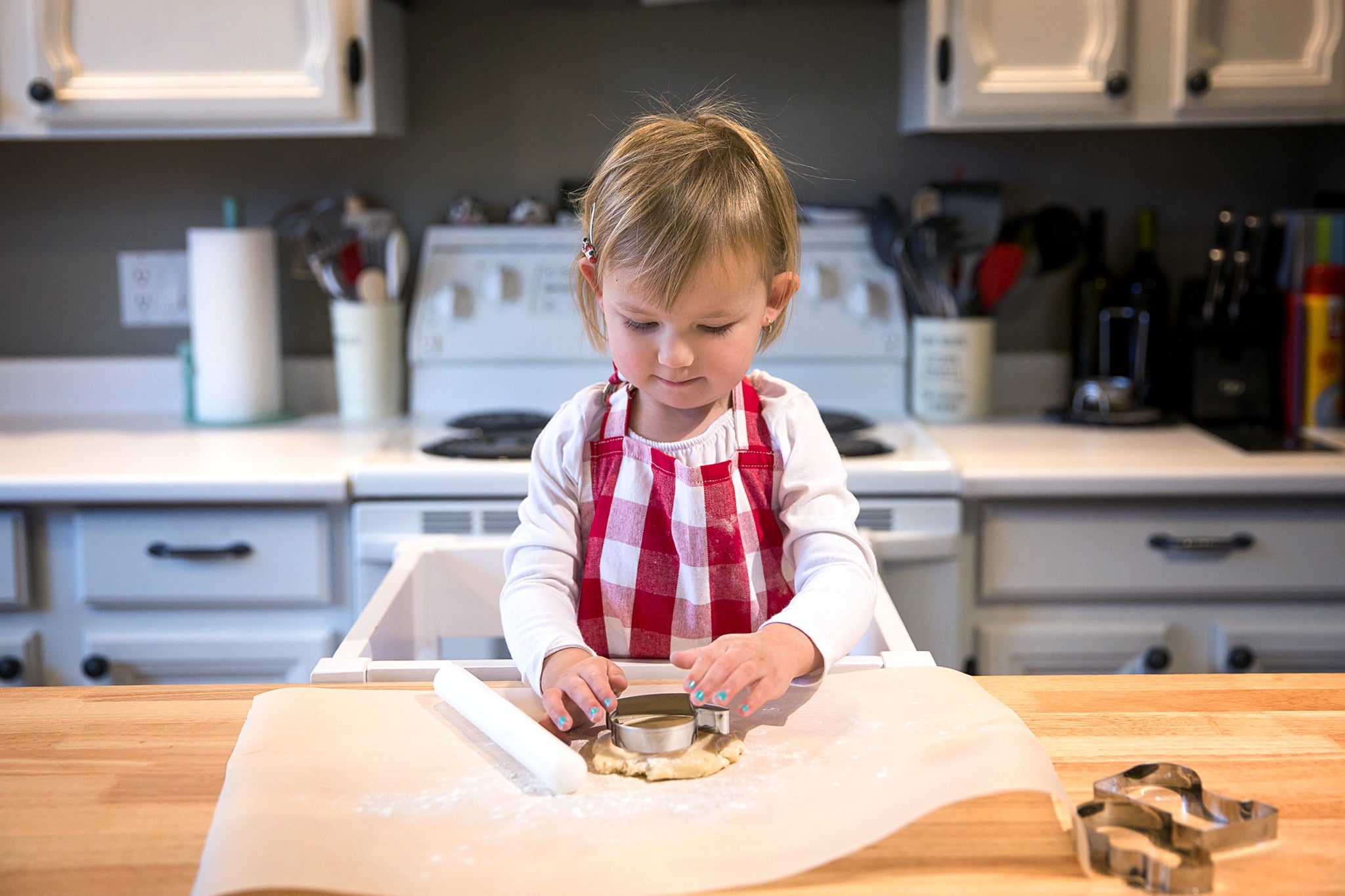 Child joyfully making cookies on a kitchen counter.